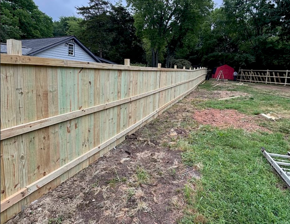 1781706824031_Screenshot-2026-06-17-at-10.33.32a-AM Homeowner inspecting backyard fence latch outdoors